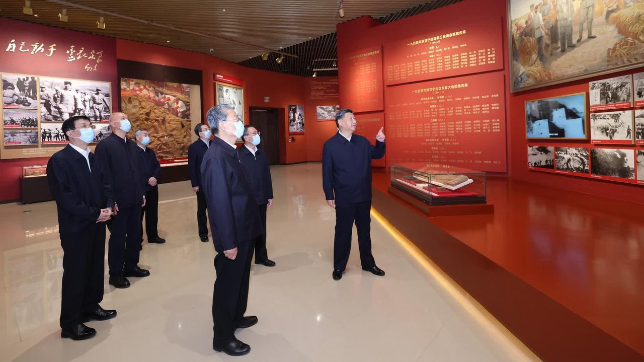 展陈馆内的团体参观场景，参观者在红色主题展厅中观看展板。