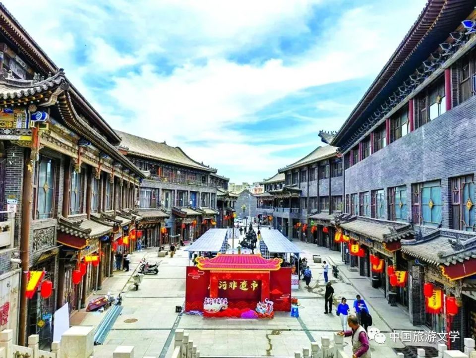 金街主街夜景，青砖灰瓦的二层铺面在灯光下显出暖黄色调，檐下红灯笼排列整齐。