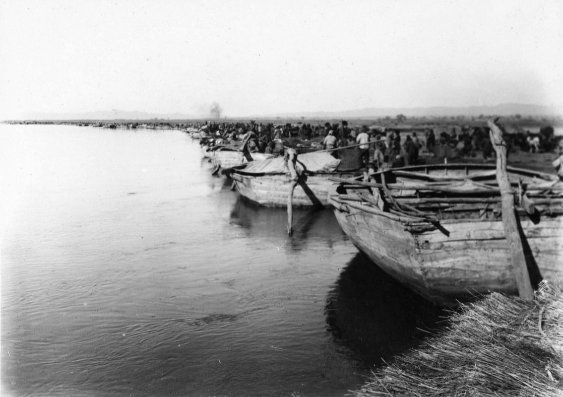 1920-30年代包头郊外的黄河船筏停靠点。河水开阔，对岸平坦，筏子和木船沿岸排列。