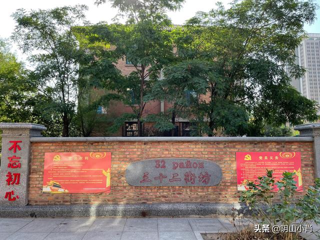 钢32街坊入口处的红色砖墙，墙面保留着"三十二街坊"和"32 район"（俄语）双语标识，以及党建宣传栏。