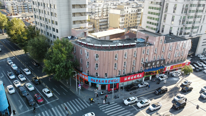 建筑转角弧面和纵向线条外观,底部可见商业橱窗