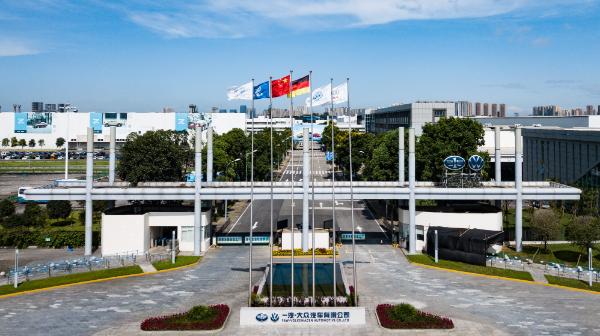 一汽-大众长春工厂正门，灰白色钢结构与玻璃幕墙组合的现代厂房前飘扬着中德两国国旗