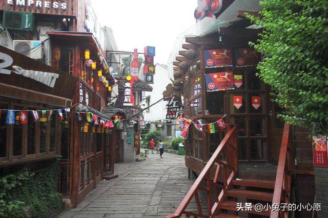 化龙池白天街景，石砌路面和两侧传统建筑，远处可见青瓦屋顶轮廓