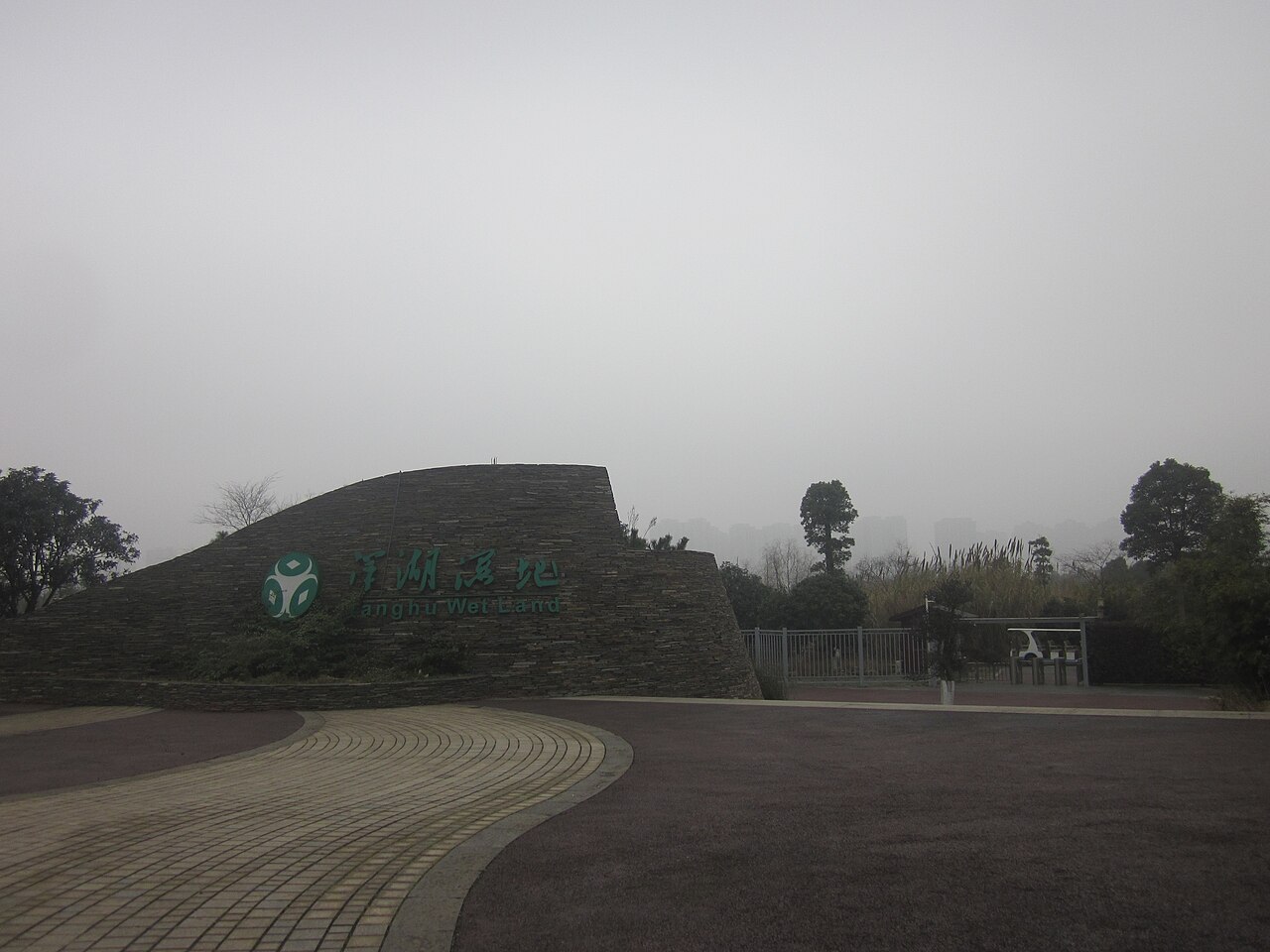洋湖湿地公园航拍全景：水面被栈道分割成整齐区块，周边是高层建筑