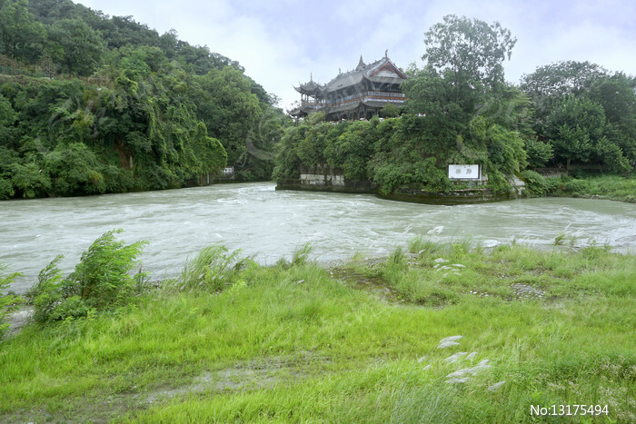 A traditional Chinese pavilion is perched on a lush, green h