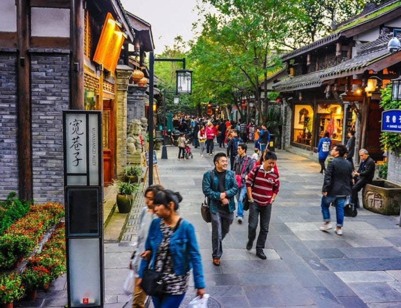 People are strolling along a lively, traditional alley with