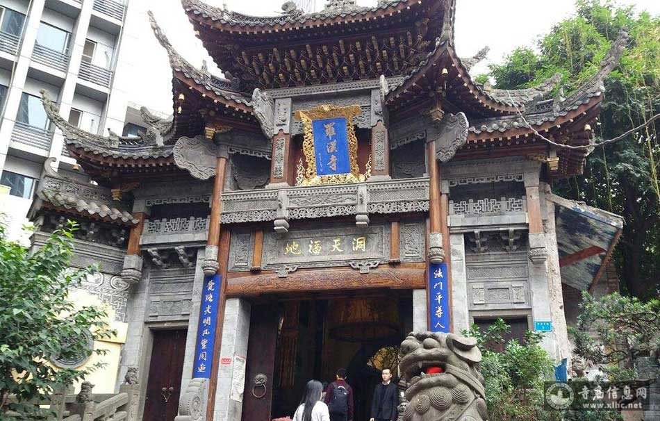 罗汉寺山门近景，朱红色大门与飞檐翘角，门前石狮子守护着寺庙与商业街的分界线