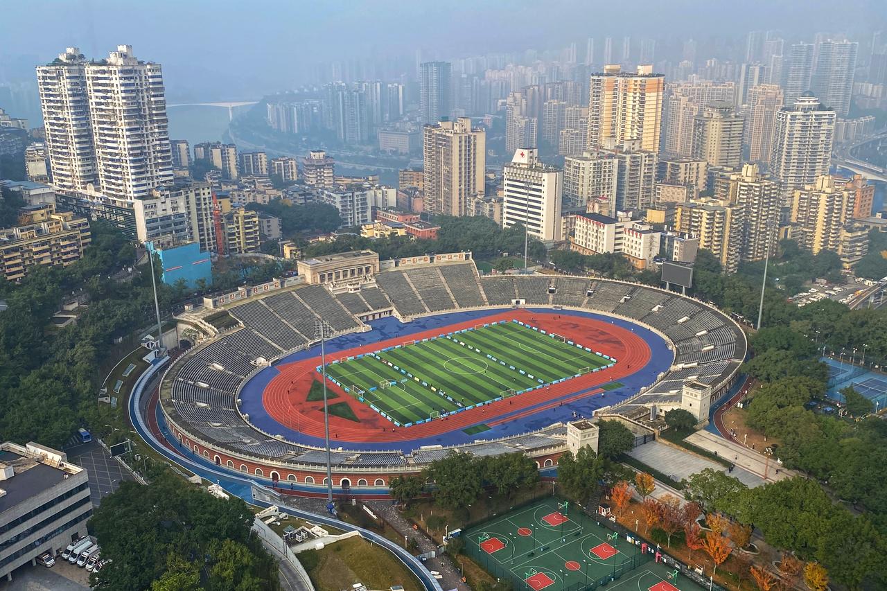 大田湾体育场全景,红色跑道环绕绿茵足球场,远处被建筑环绕