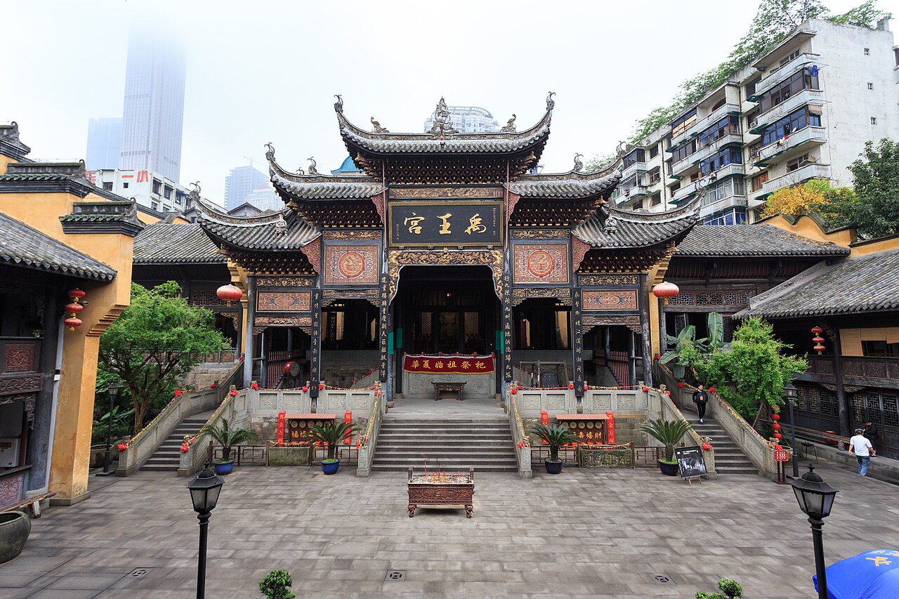 湖广会馆建筑群鸟瞰，黄色琉璃瓦屋顶层层叠落，与远处现代高楼对照