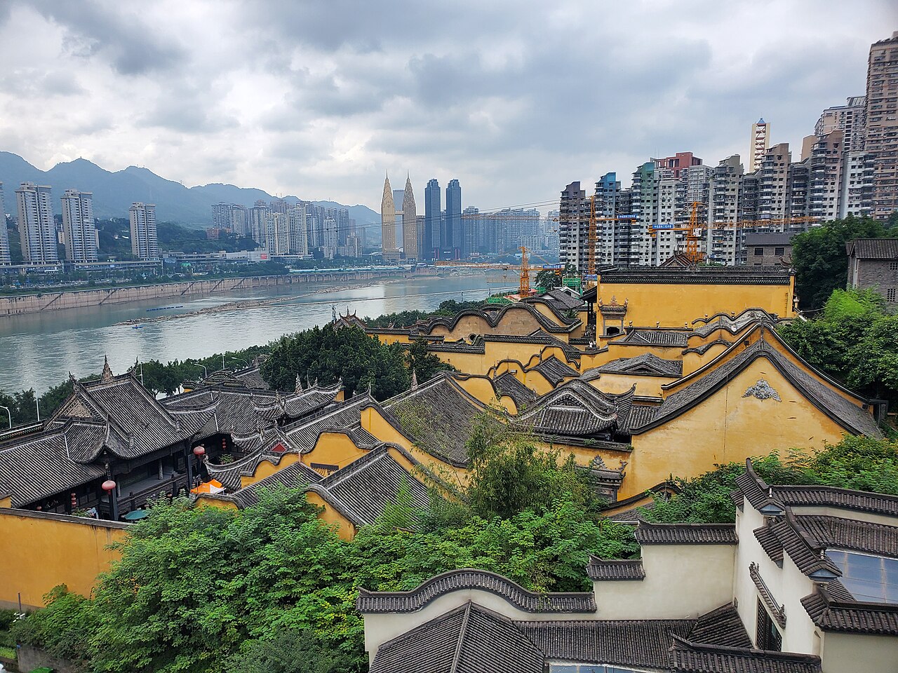 湖广会馆沿江立面，黄墙碧瓦，背后是长江和现代桥梁