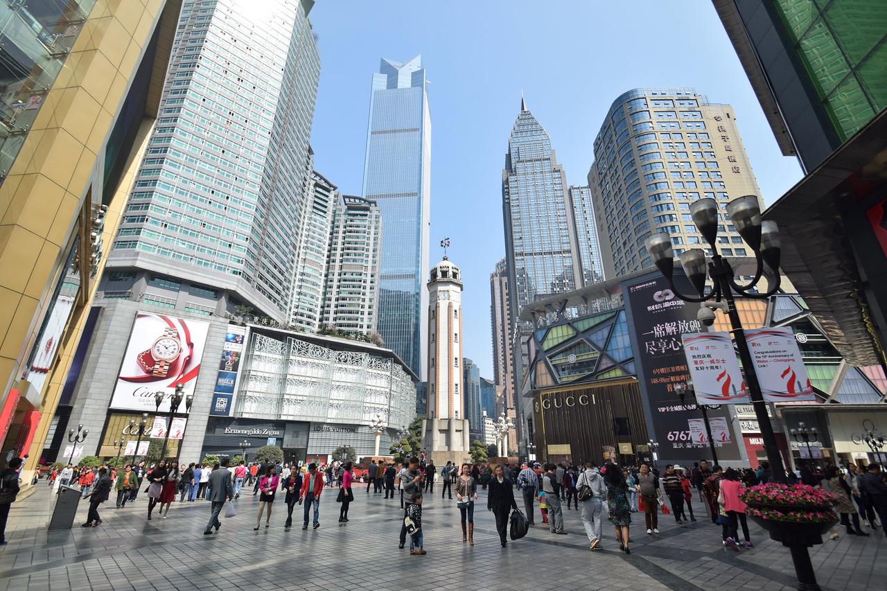 解放碑全景，白色八角形碑身在商业建筑环绕中矗立于步行广场中央