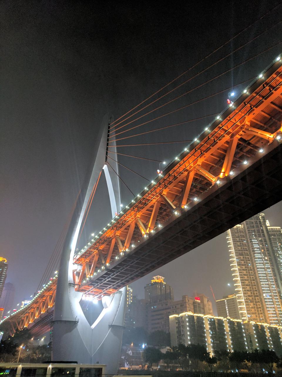 从江北嘴看千厮门大桥和洪崖洞夜景，桥塔亮灯后形成清晰的钻石轮廓