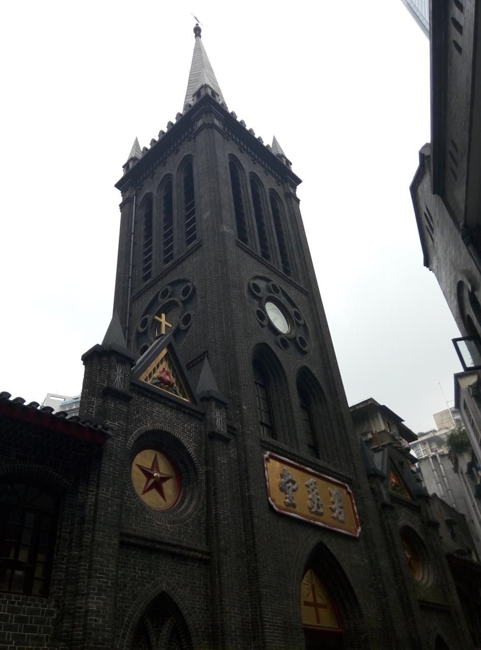 若瑟堂钟楼正面外观,青灰色砖石立面,山字形钟楼和红色十字架