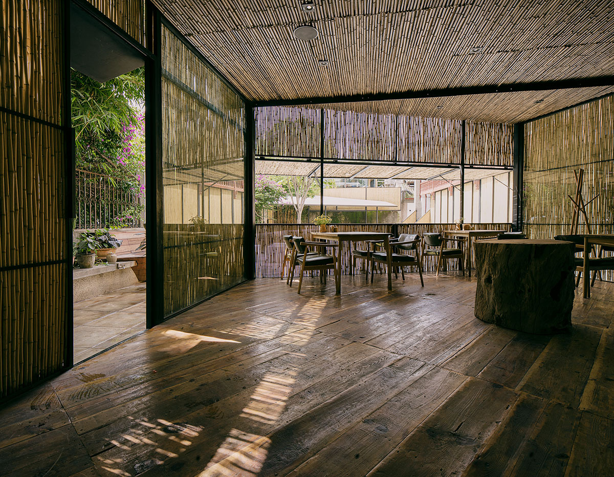 柴米多农场餐厅庭院全景，从左到右依次为白族木结构老屋（西侧竹格栅推拉门）、庭院中央的钢结构竹亭、以及北侧两层餐厅的外立面