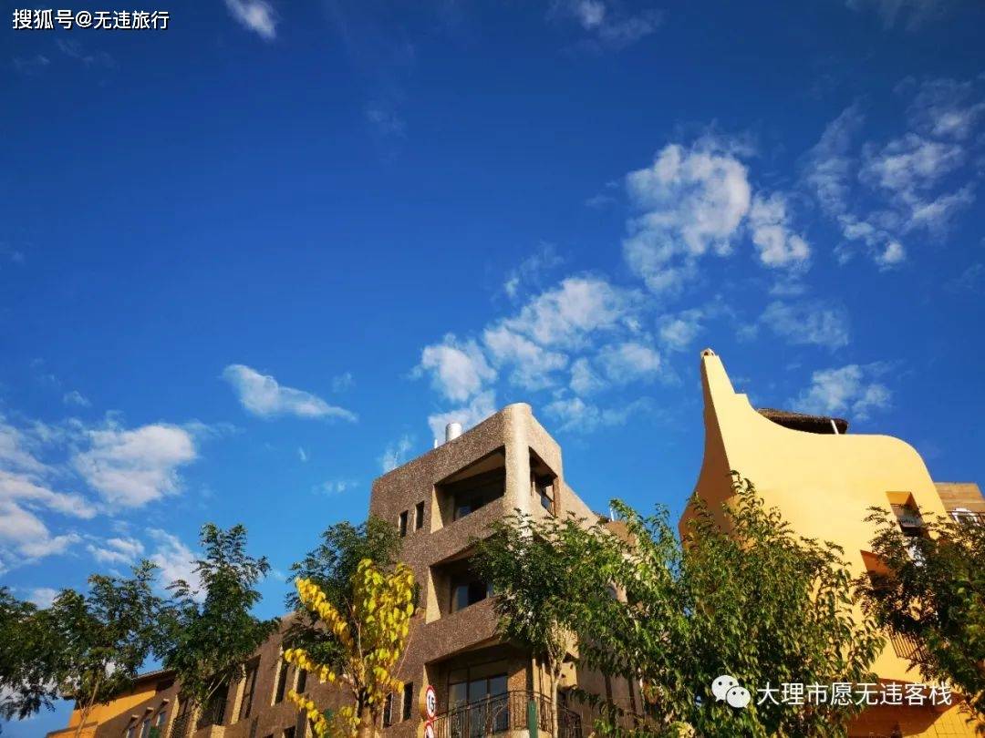 理想邦建筑群的弧形线条和有机形态，暖色墙面在蓝天映衬下
