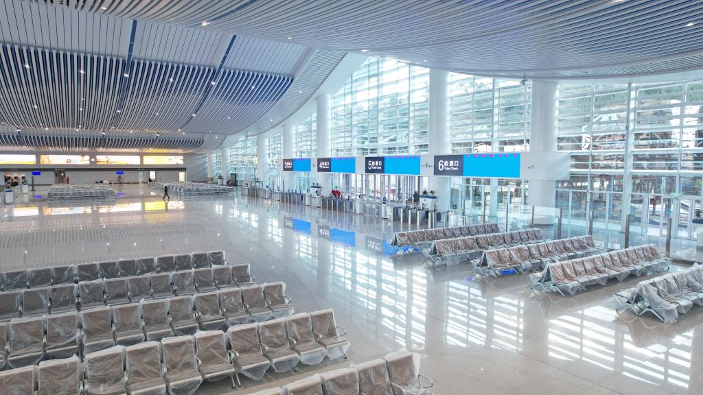 The station features a spacious, modern waiting area with rows of empty seating, large glass windows
