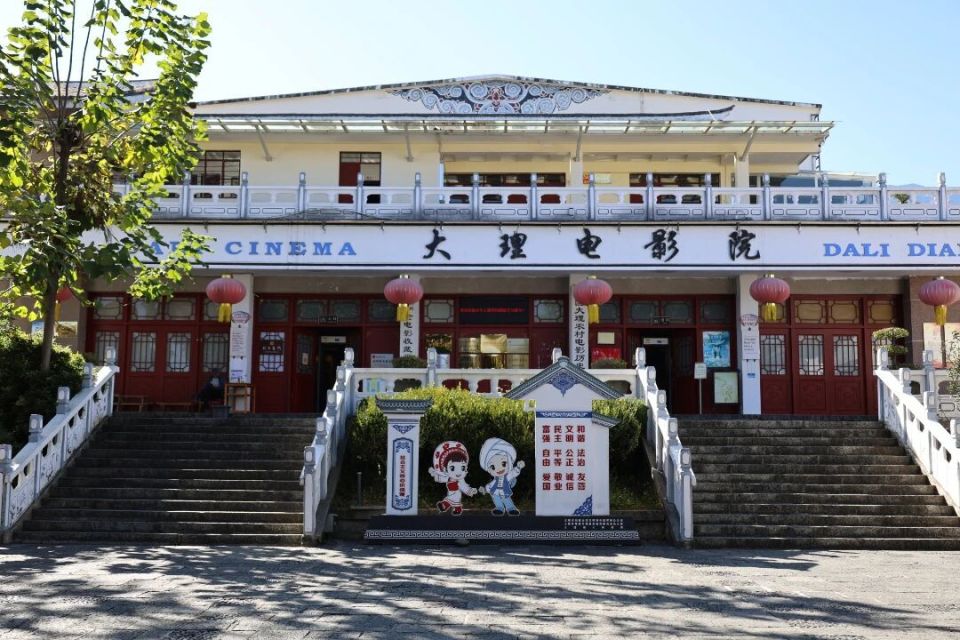 大理农村电影历史博物馆建筑外观:青瓦白墙的白族风格建筑,门头悬挂木质匾额,与周围旅游商品店形成视觉反差