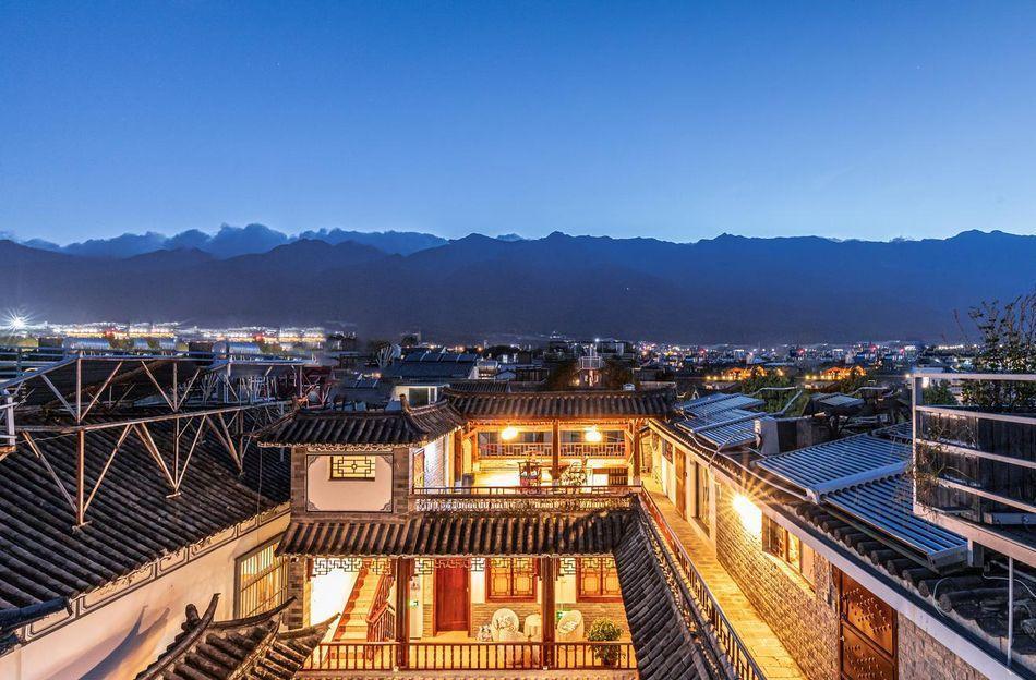 The rooftops of traditional buildings with tiled roofs and wooden details are illuminated against a 