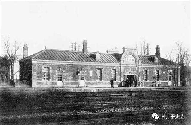 A historic brick building with a central arched entrance and a person standing n