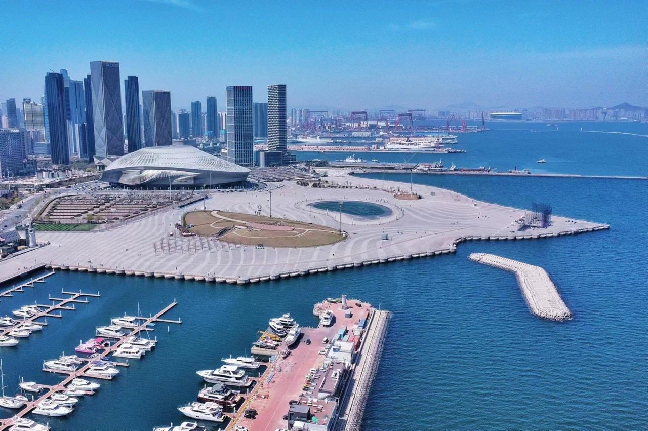 A modern port in Dalian with a marina, high-rise buildings, and a large coastal 