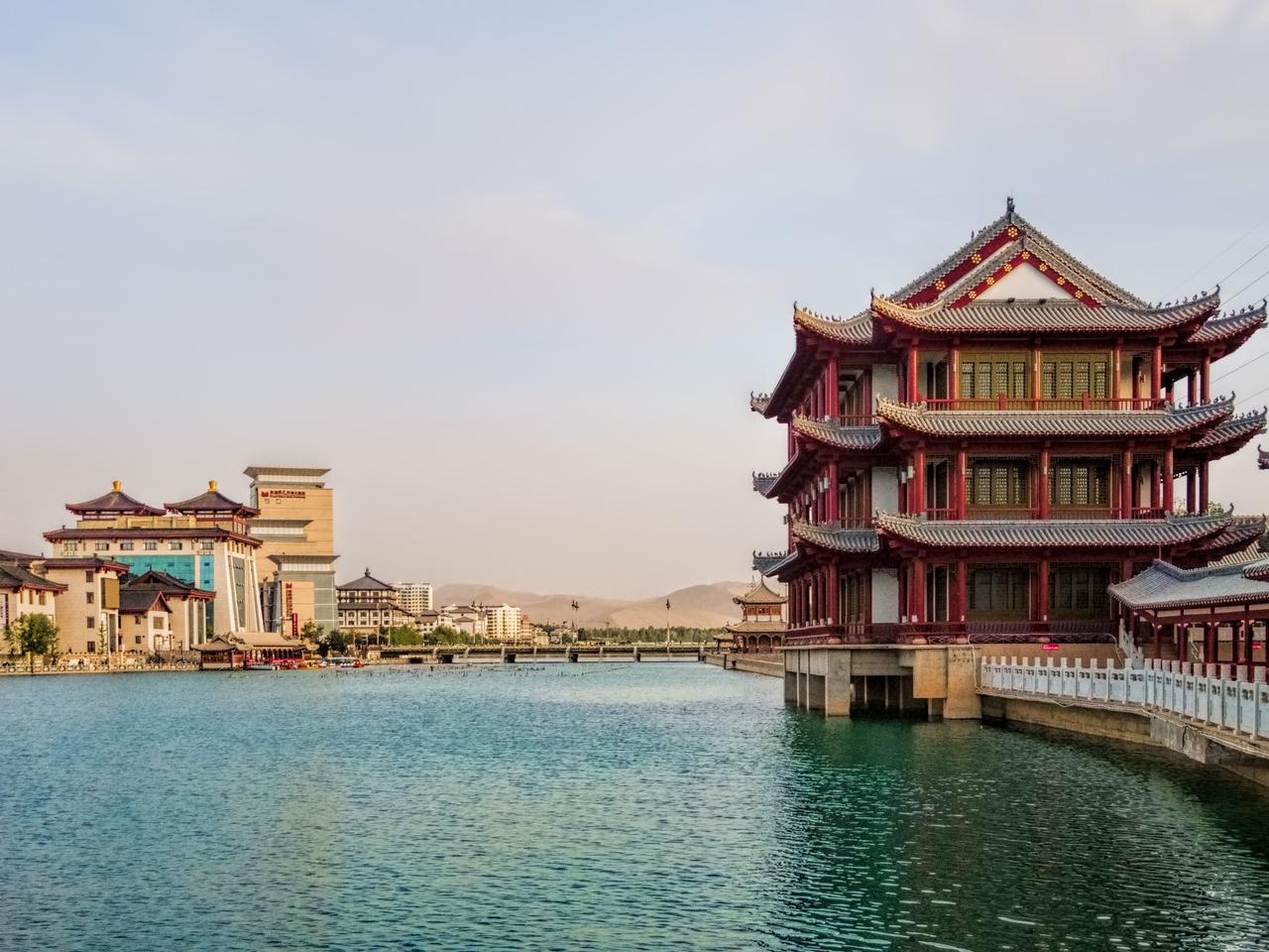 党河在敦煌城市段的水岸景观，远处鸣沙山沙丘在绿洲南缘升起