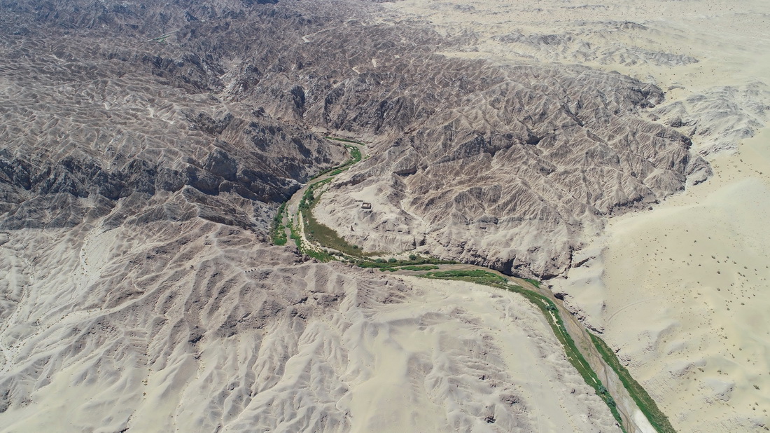 站在莫高窟崖顶南瞰：宕泉河谷蜿蜒穿过峡谷，远处可见鸣沙山的轮廓