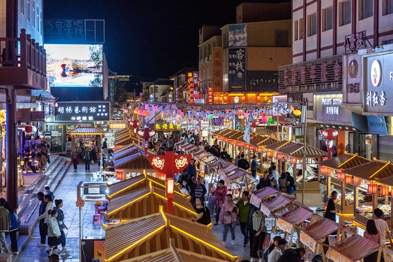 敦煌夜市夜间景象，灯笼和摊位构成丝路主题消费空间