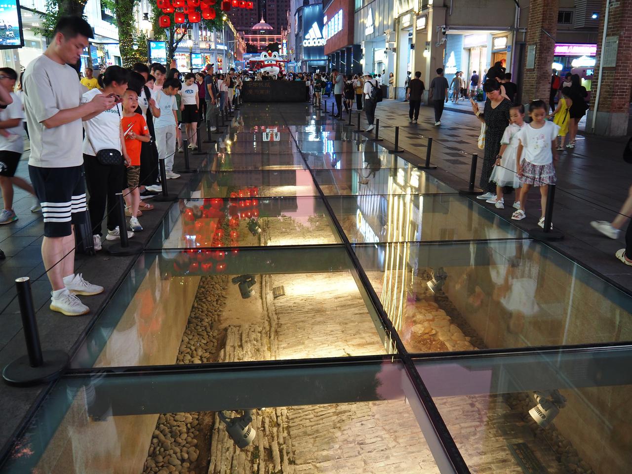 北京路步行街路面上的玻璃钢罩，下方可见多层历史路面