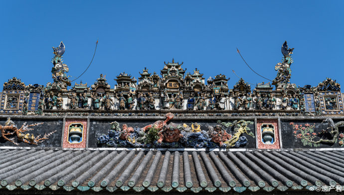 A richly decorated roof of the Chen clan ancestral hall in Guangzhou features intricate ceramic sculptures, dragon figur