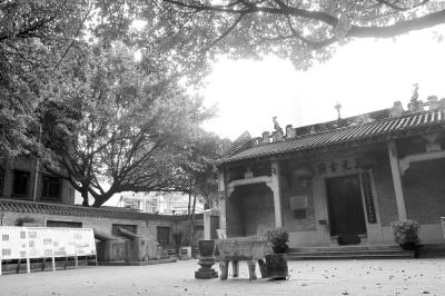 A traditional Chinese building with architectural features and commemorative plaques, surrounded by trees and stone orna