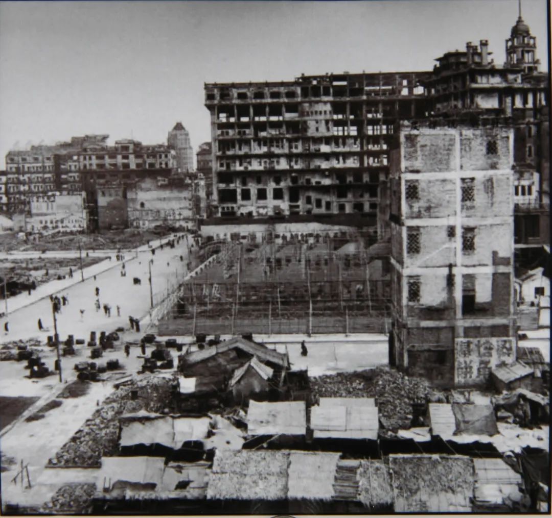 A construction site with the foundation and ground paving of a commercial building, surrounded by unfinished structures 