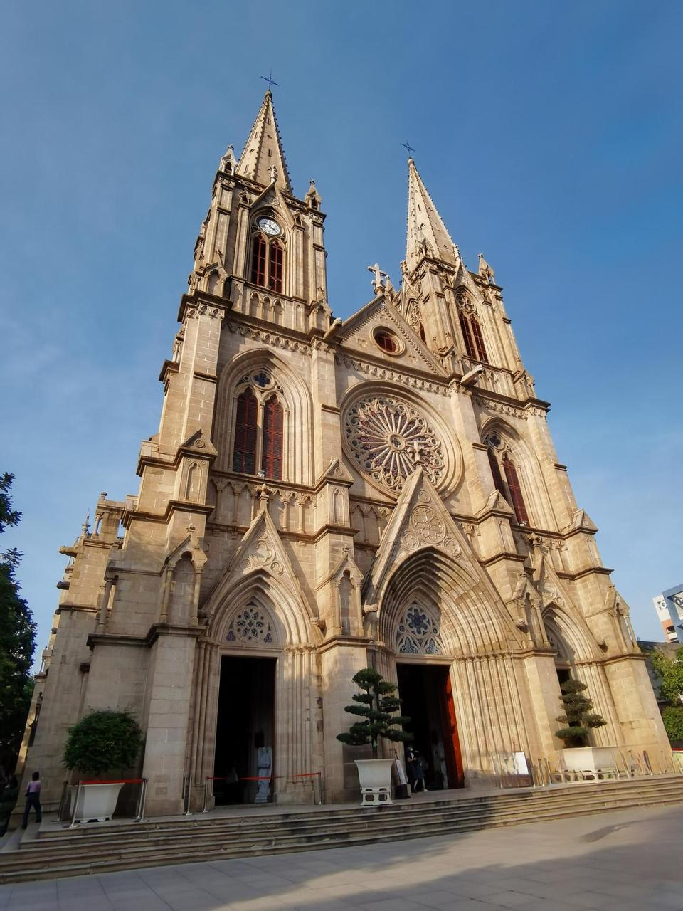 A grand Gothic-style stone church with pointed arches, intricate facade details, and twin spires stands against a clear