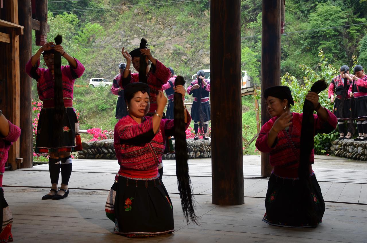红瑶女性在表演场上展示长发舞蹈,红色传统服饰在绿色山野中格外醒目