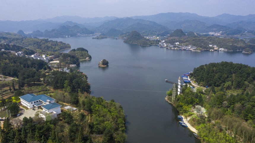春日百花湖：游船在湖中行驶，远处群山环抱