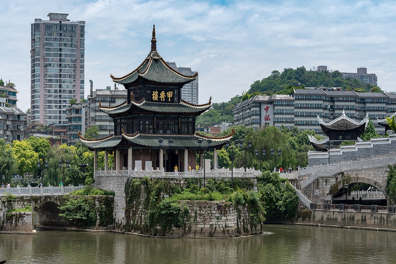 甲秀楼正面，三层绿色琉璃瓦顶立在鳌矶石上，浮玉桥从楼底穿过