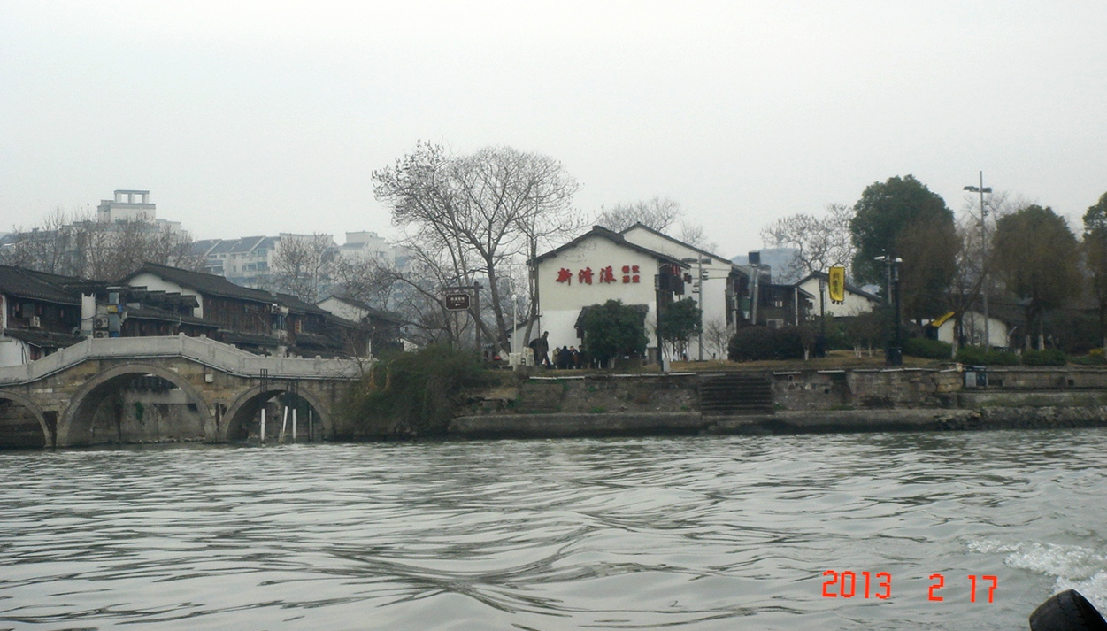运河上的水上巴士停靠小河直街站,背景是白墙黑瓦的民居建筑群