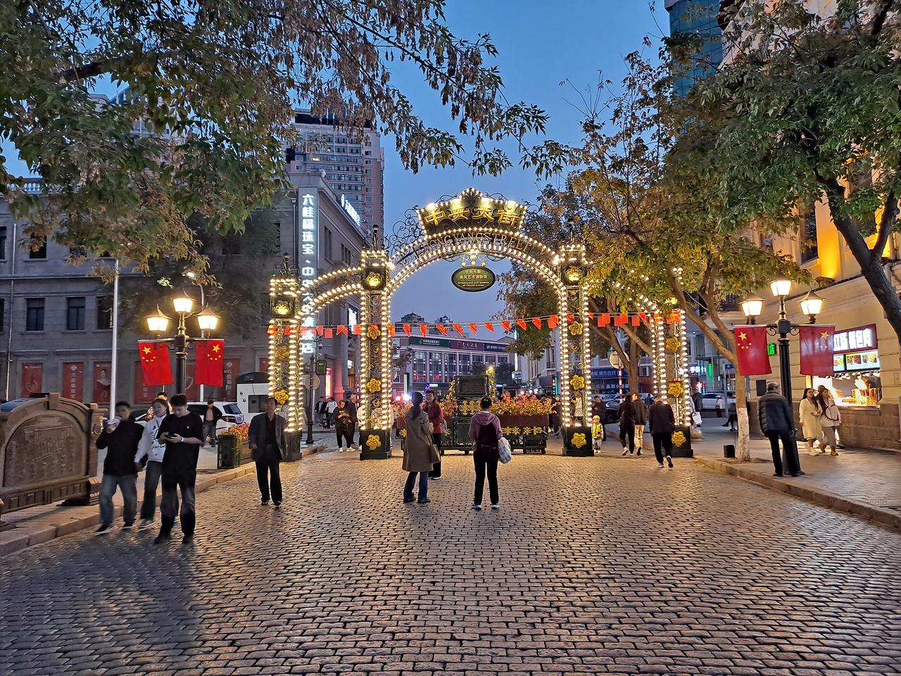 中央大街冬季夜景，冰灯装置取代了夏季的绿化，羽绒服人群在寒夜里穿行