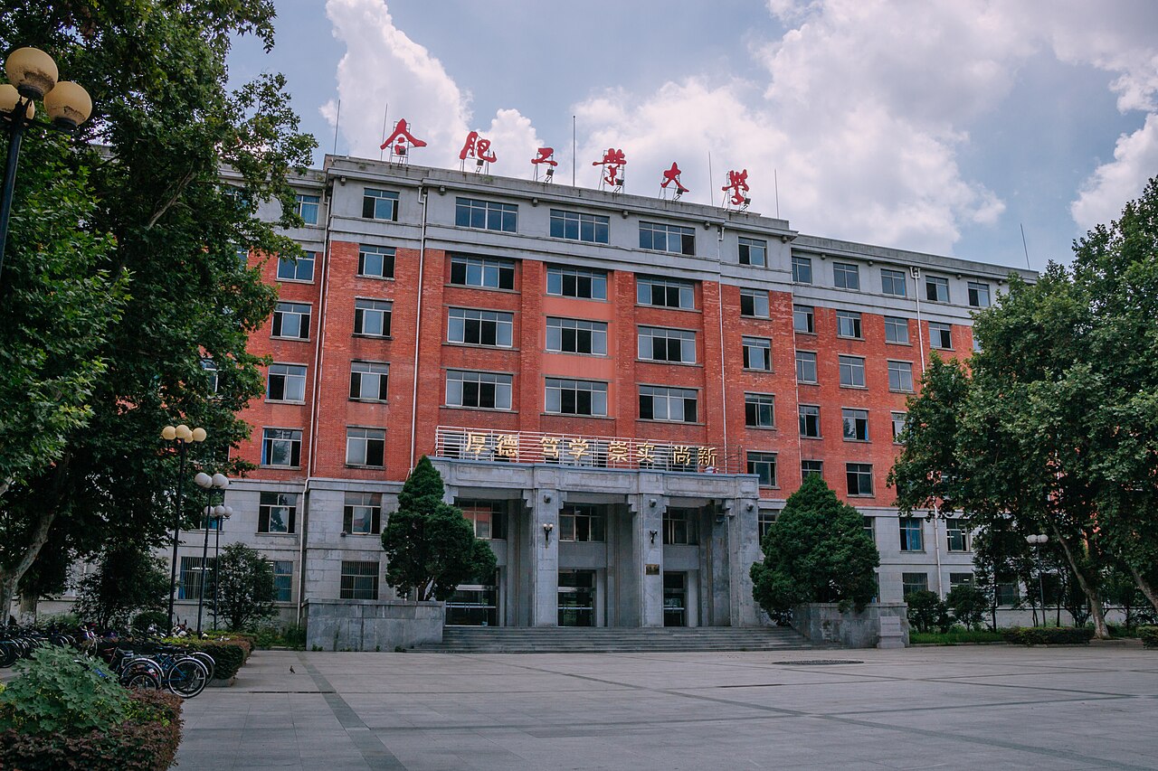 七层红砖主楼的正面影像，白色基部和檐口、中央尖塔和广场前场清晰可见