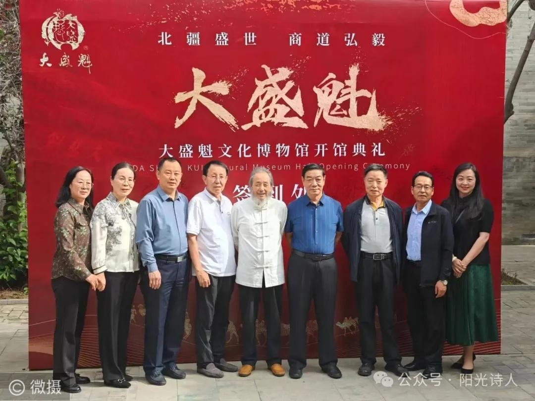 A group of nine people stands in front of a red banner at the opening ceremony o
