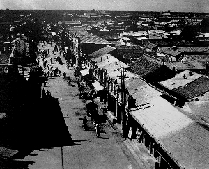 A bustling street scene in an old town area with traditional buildings, shops, a