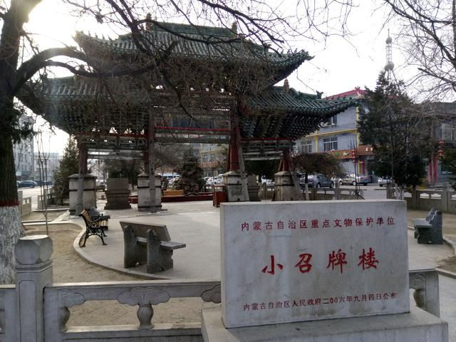 A traditional Chinese pavilion with curved, ornate roof tiles stands in a small 