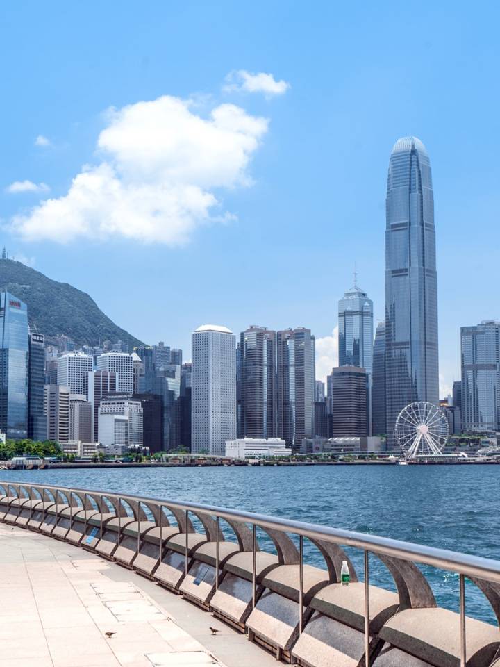 从中环海滨长廊眺望维多利亚港和九龙半岛，远处可见西九文化区和太平山轮廓。