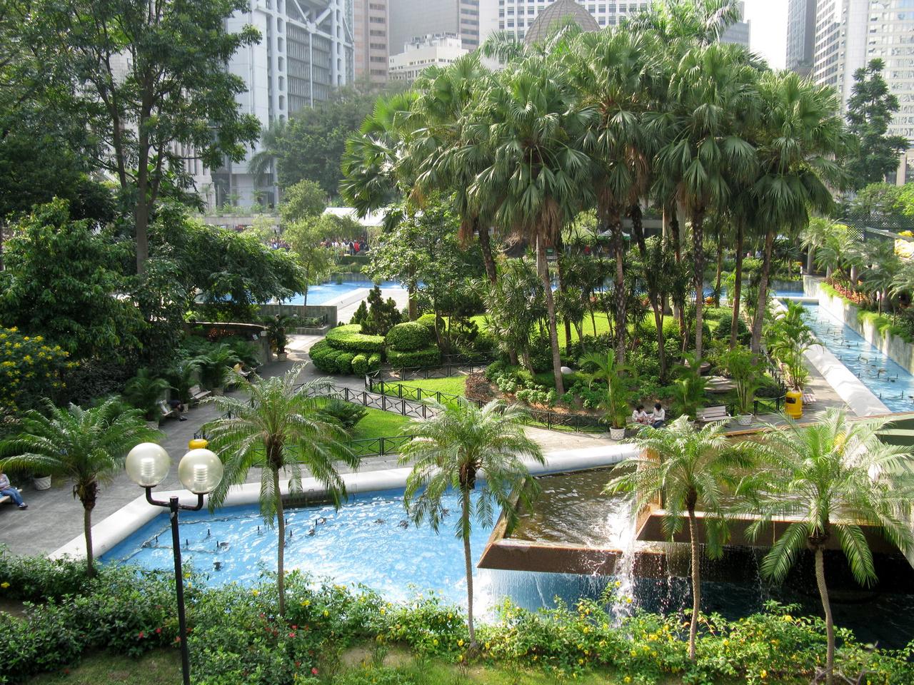 遮打花园现状，矩形水池和步道，远处可见立法会大楼。