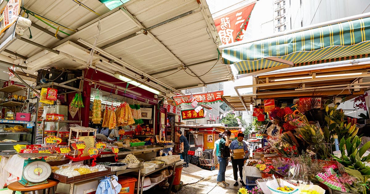 嘉咸街市中段的排档和遮阳帆布，唐楼两侧的雨篷在街道上空形成半室内的空间感