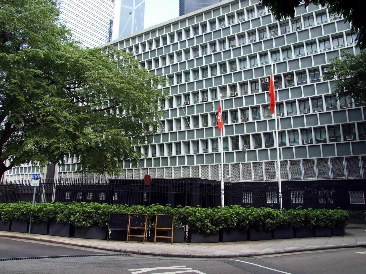 从下亚厘毕道看中区政府合署中座立面，灰色混凝土框架和统一钢窗构成标准模数立面，建筑高度刻意压低，四周绿树环绕。