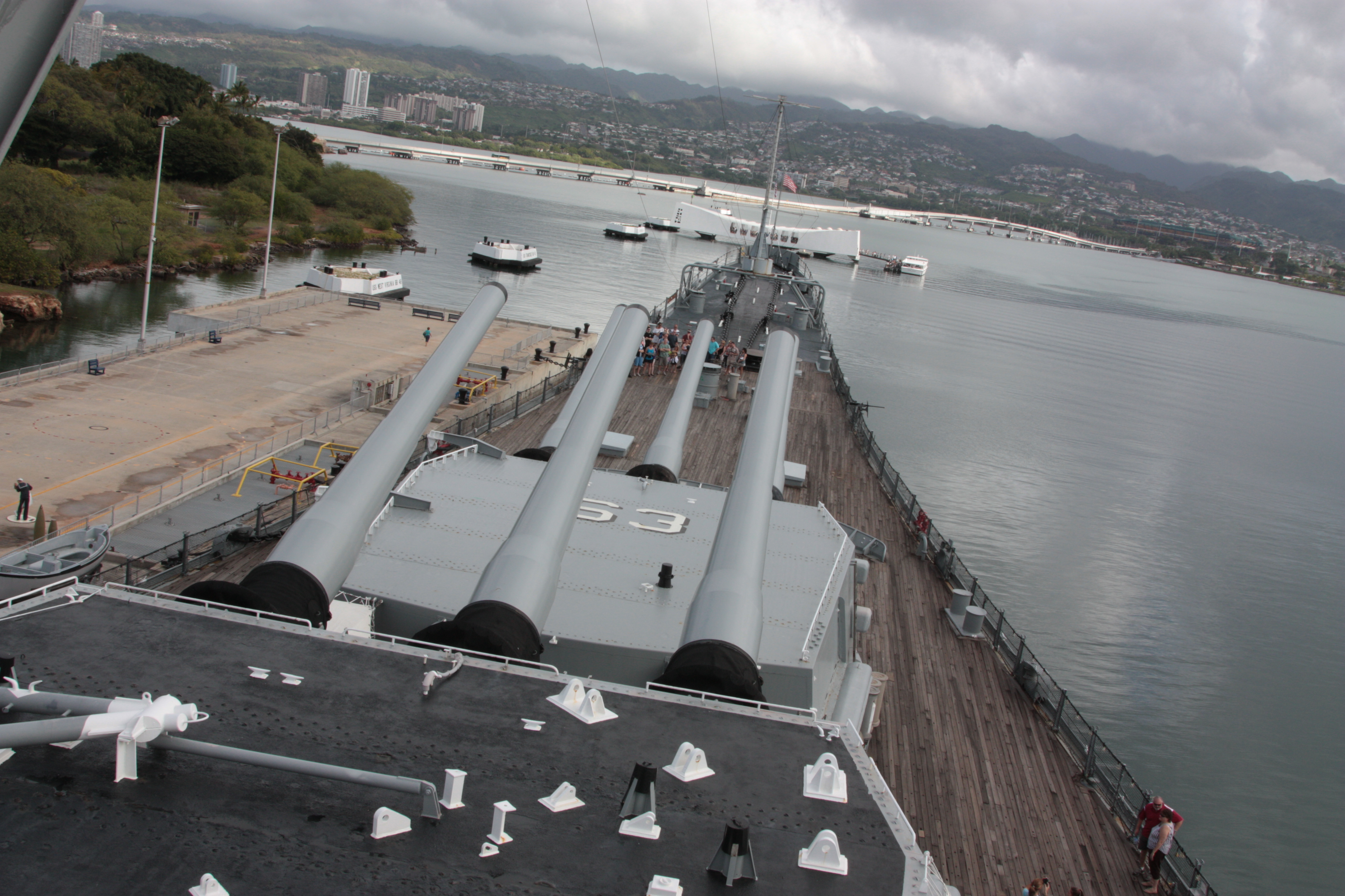 Forward turrets 的 16-inch 炮管指向远方，Arizona Memorial 在水面另一端的背景中清晰可读