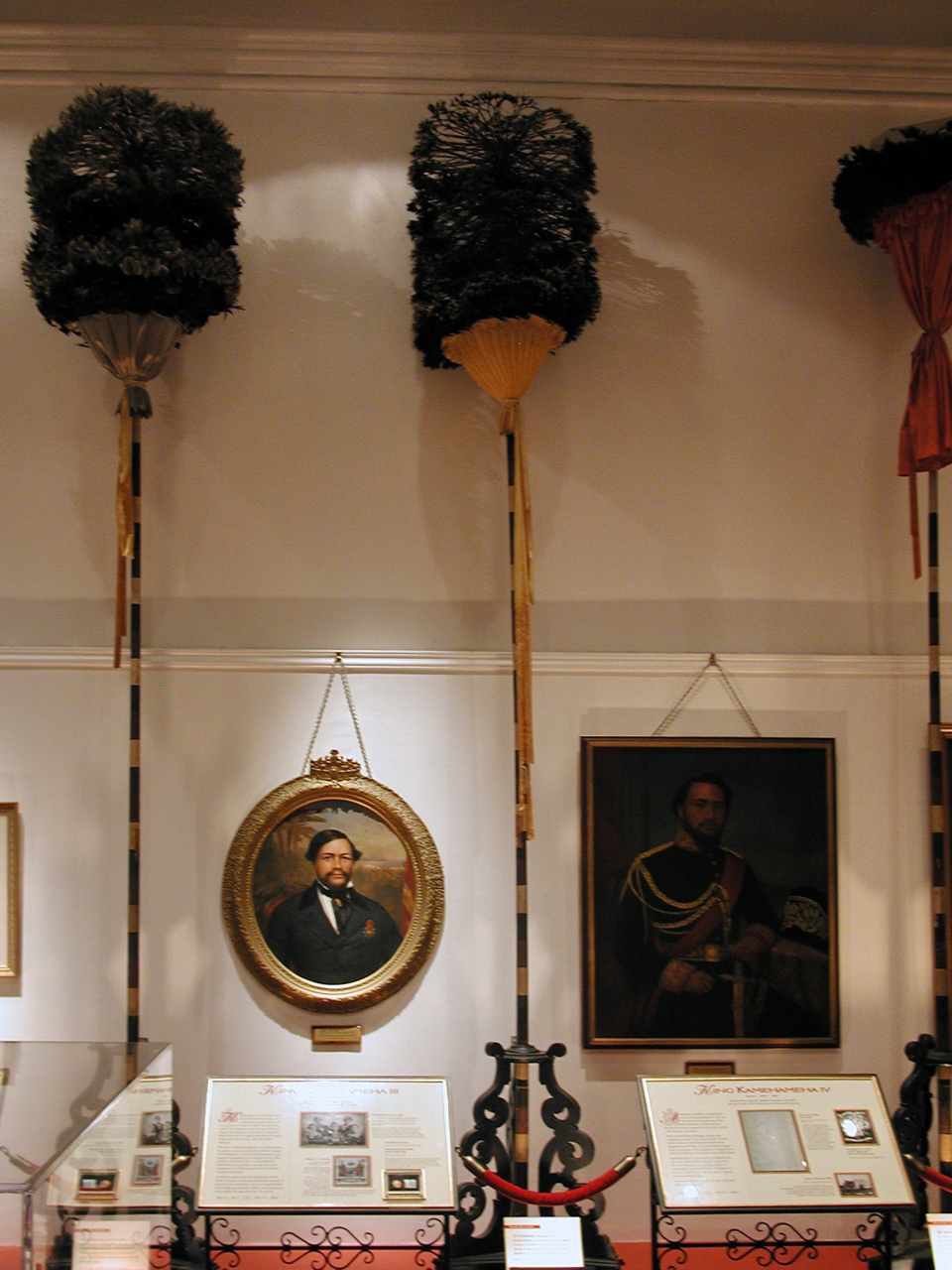 Kāhili Room 内的 feather standards 与 royal portraits 并置
