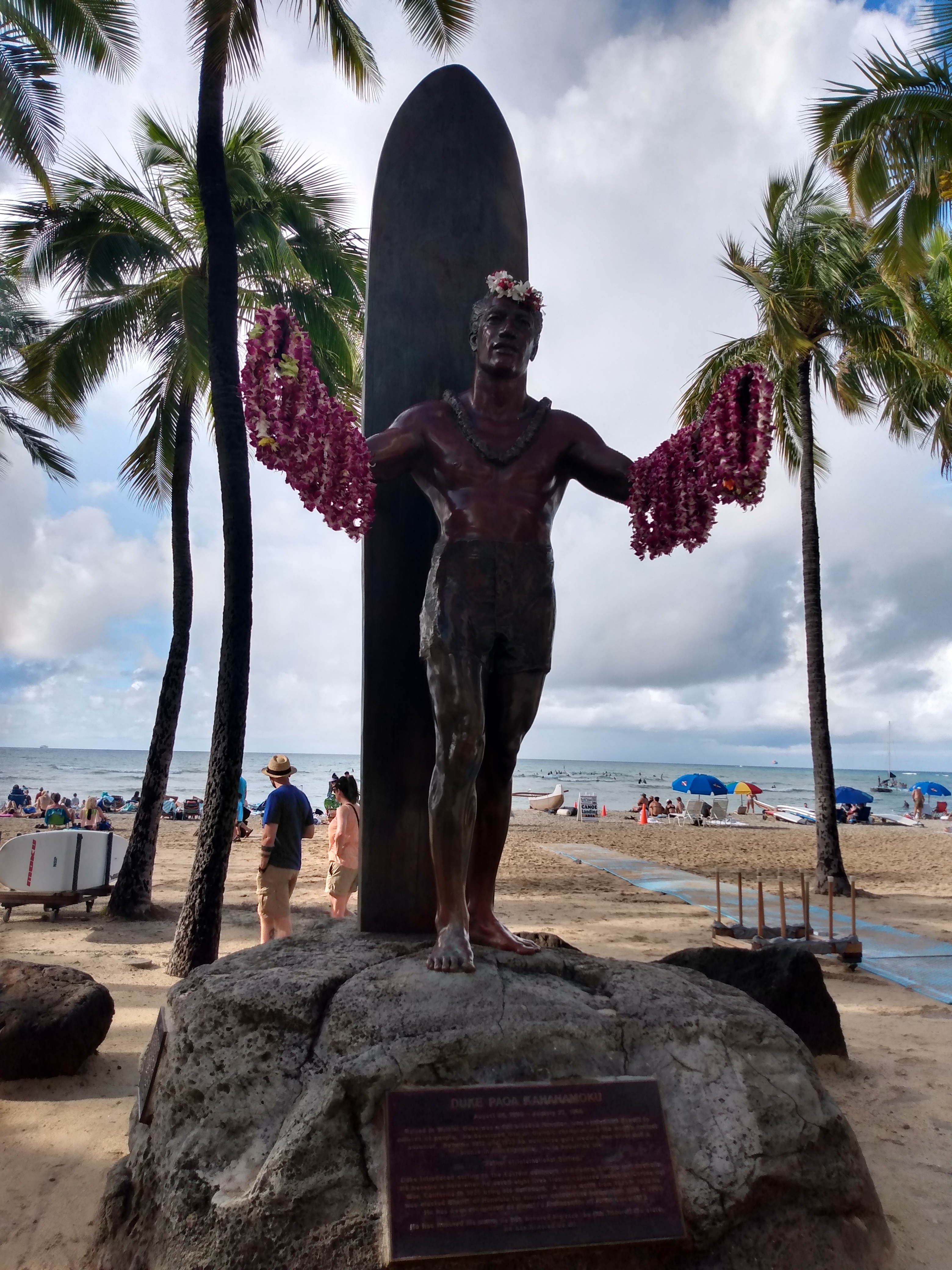 Duke Paoa Kahanamoku 铜像正面，张开双臂姿态和 lei 展示其旅游前台界面