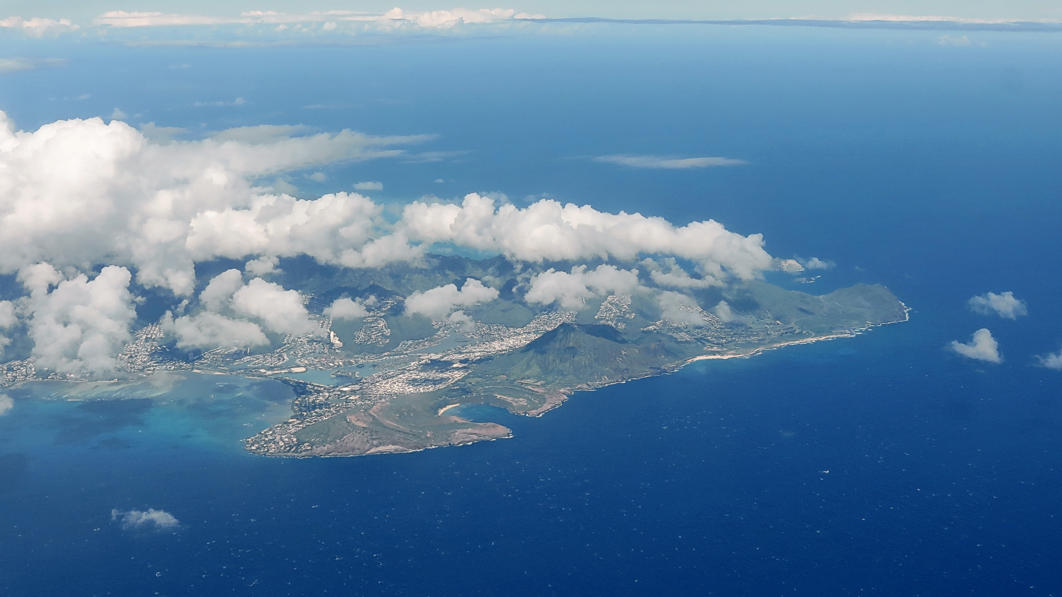 Hanauma Bay 与 Koko Crater 同框：从高处看 bay 的弧形、两侧 tuff wall 和远处 Koko Crater 的火山轮廓