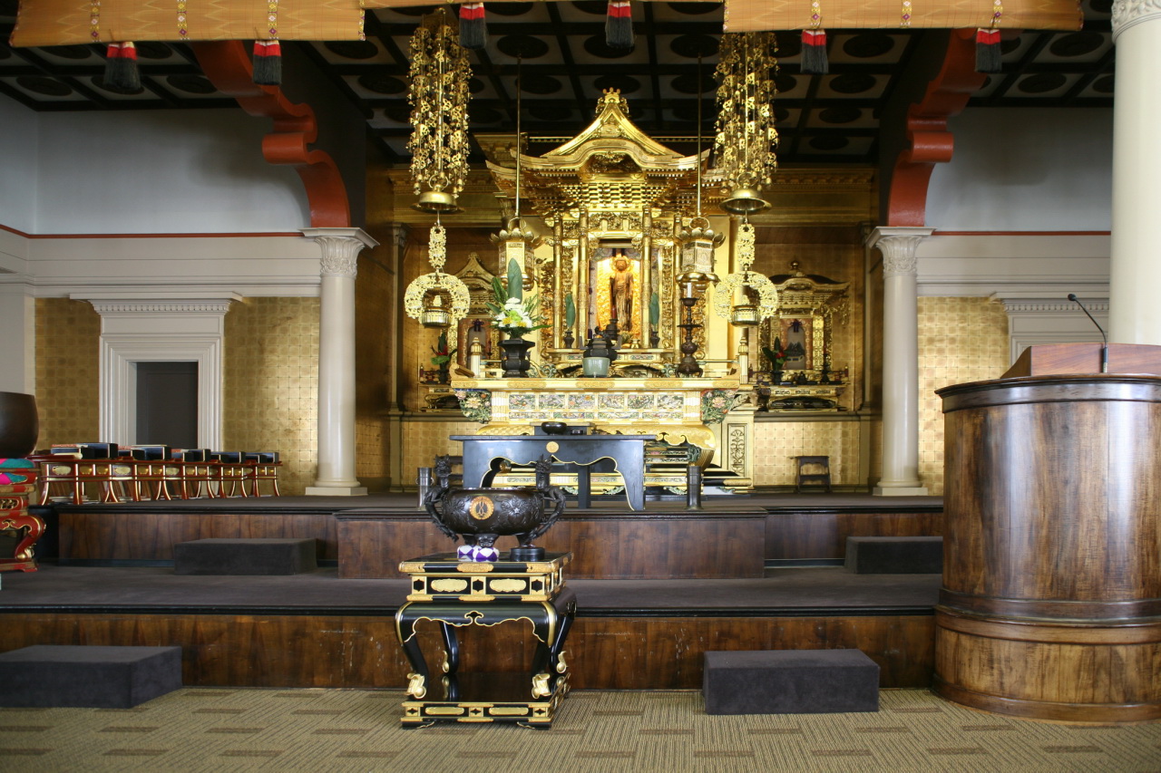 Honpa Hongwanji Hawaii Betsuin 的 central altar，gold and brass decorations、Amida Buddha 像与 pews、central aisle、pipe organ 的并置